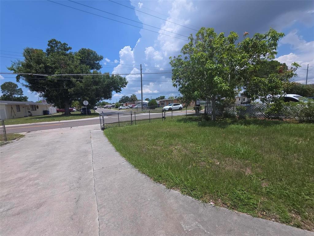 A concrete driveway leads to a grassy lot enclosed by a chain-link fence — 6015 N MANHATTAN AVENUE, TAMPA, FL