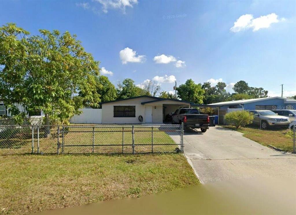 A single-story house with a concrete driveway, a chain-link fence, and a large tree — 6015 N MANHATTAN AVENUE, TAMPA, FL