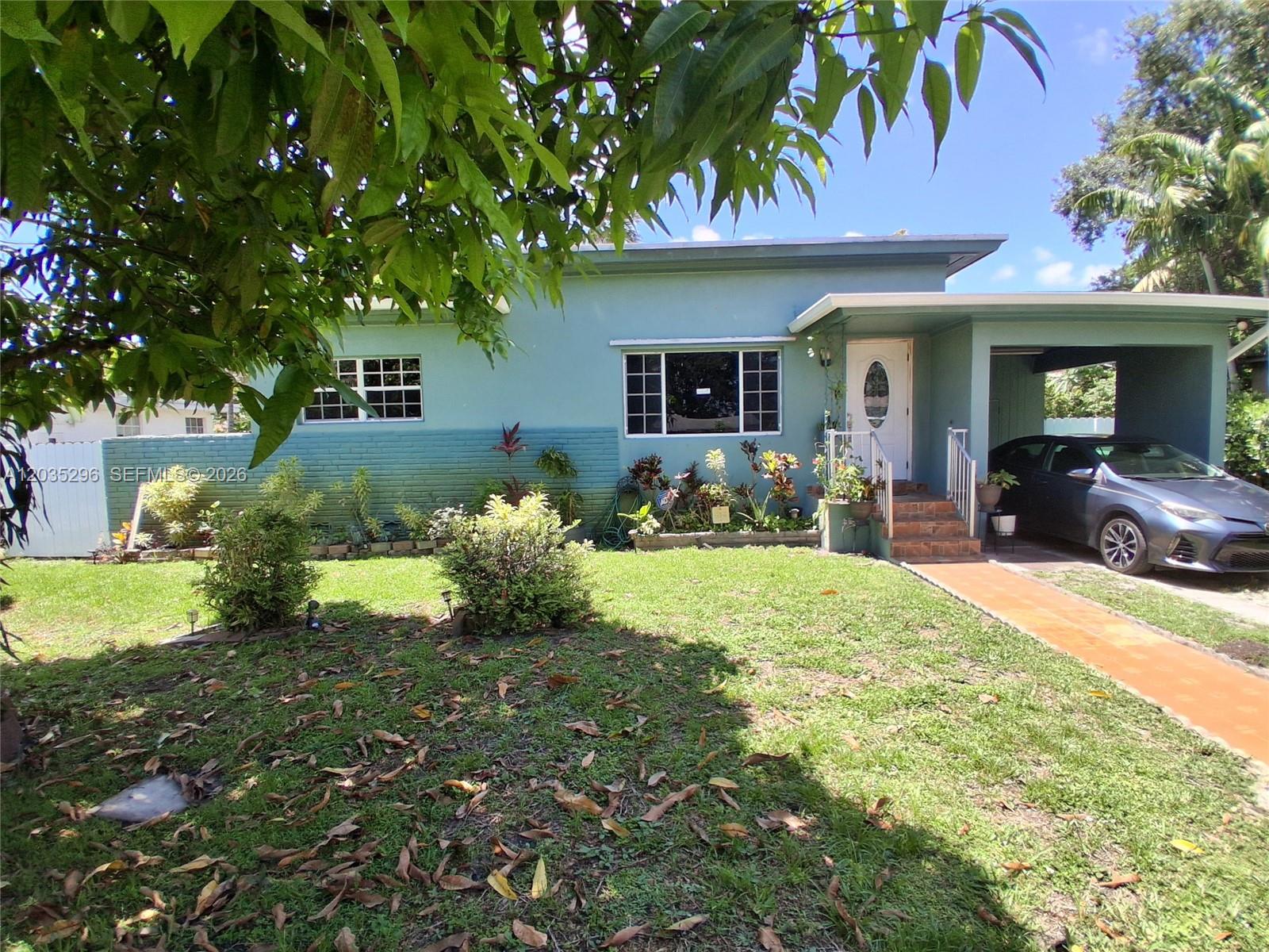 A single-story teal house with a carport and a front lawn under a blue sky — 220 NW 150th St, Miami FL 33168, MIAMI, FL