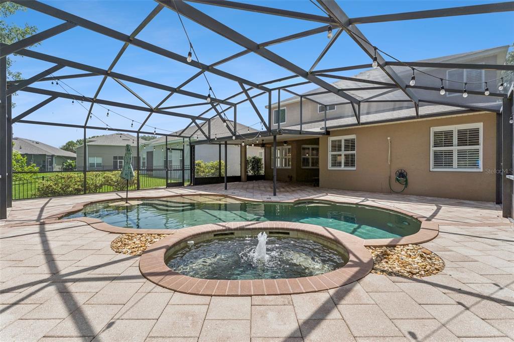 A screened-in patio features a swimming pool with an attached circular fountain and paver decking — 10109 MARSH PINE CIRCLE, ORLANDO, FL