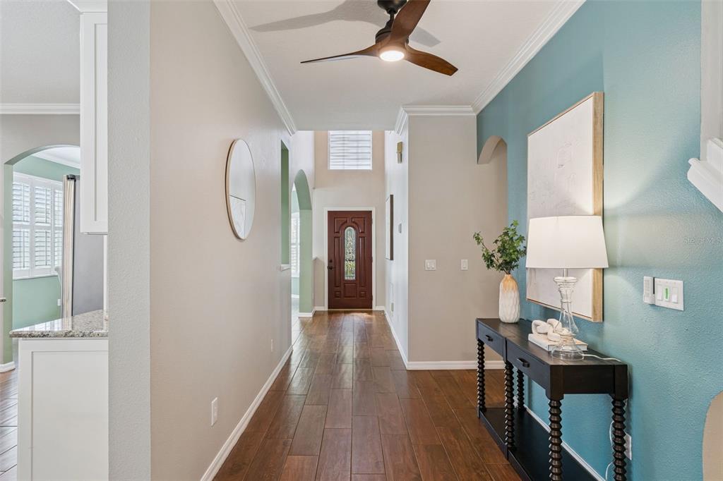 A foyer with wood-look tile flooring, a dark wood front door, and a teal accent wall — 10109 MARSH PINE CIRCLE, ORLANDO, FL