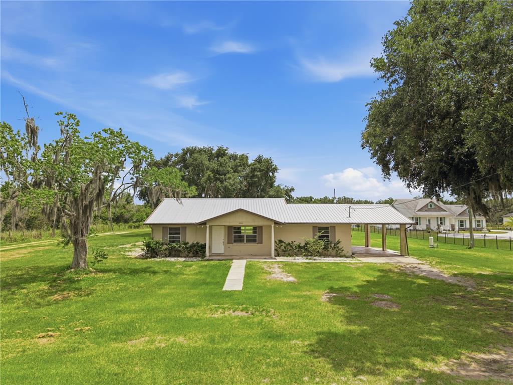 A single-story house with a metal roof and an attached carport sits on a lawn — 2000 PARKWAY AVENUE, ST CLOUD, FL