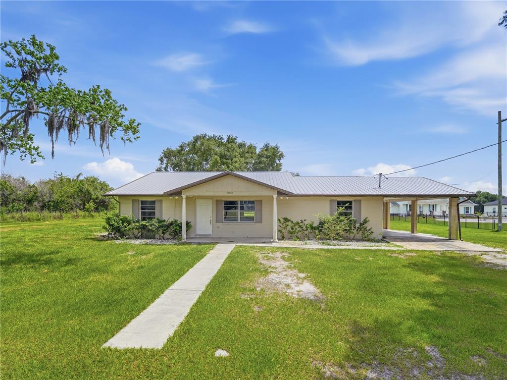 A single-story house with a metal roof, a front porch, and an attached carport — 2000 PARKWAY AVENUE, ST CLOUD, FL