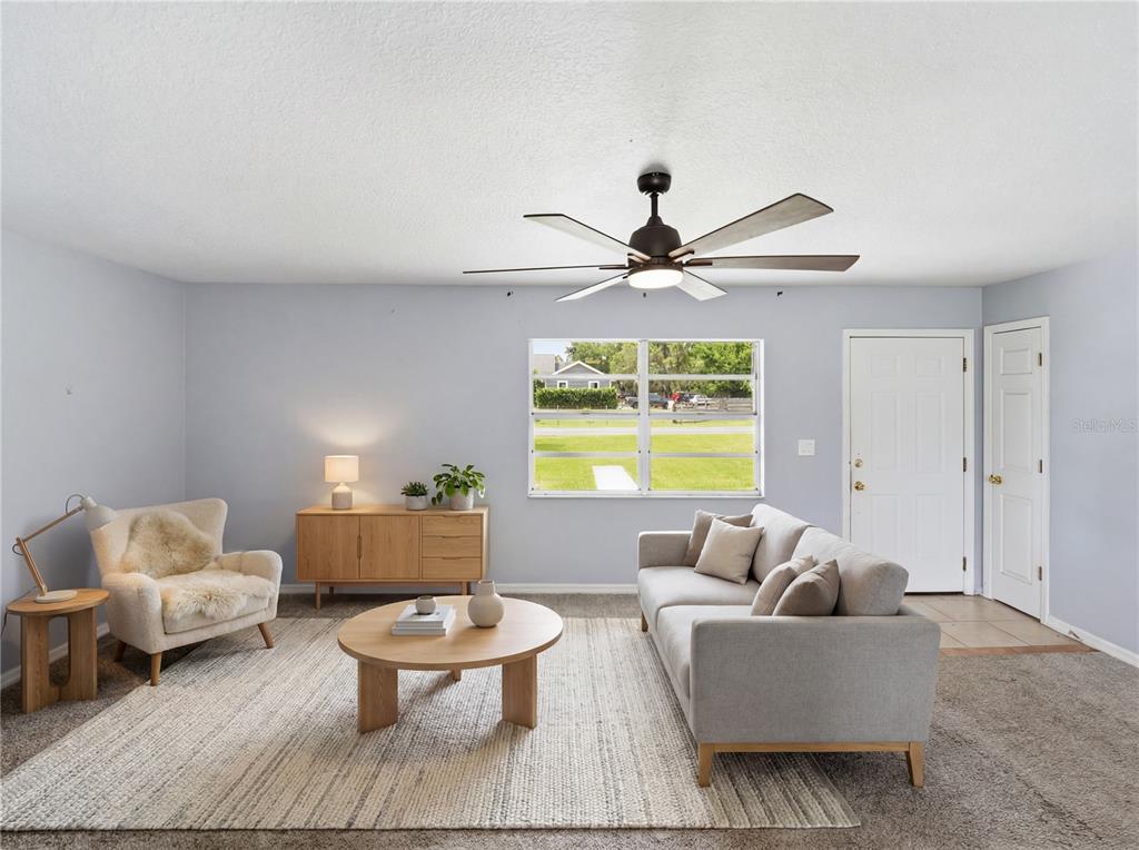 A living room features light gray walls, a ceiling fan, a sofa, and a round table — 2000 PARKWAY AVENUE, ST CLOUD, FL
