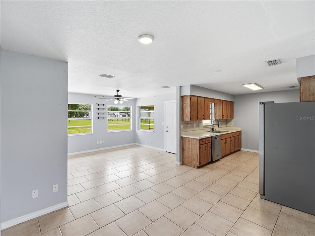 An open-concept kitchen and dining area features light tile flooring and wood cabinetry — 2000 PARKWAY AVENUE, ST CLOUD, FL