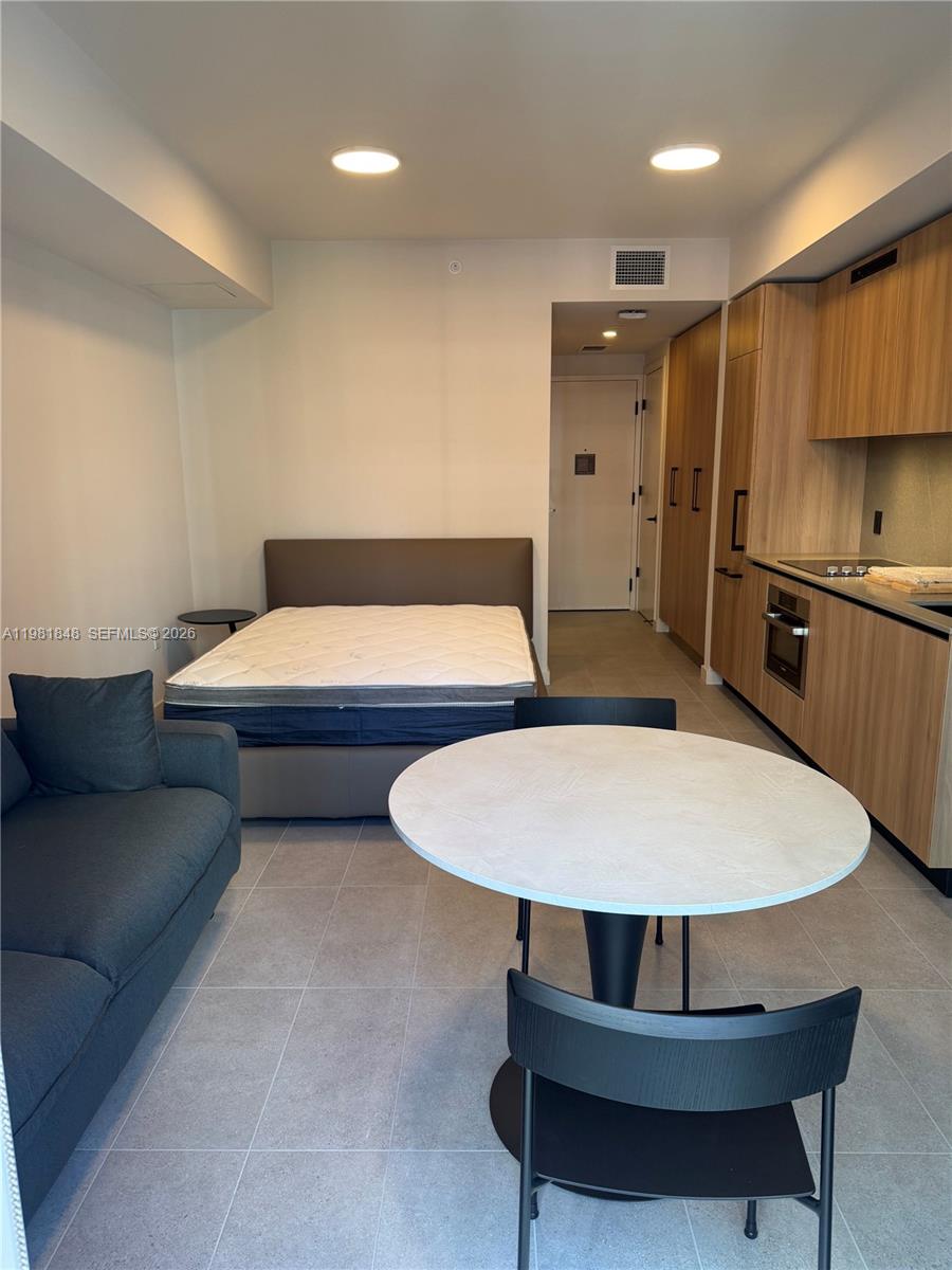 A studio apartment features a bed, sofa, dining table, and light wood kitchen cabinetry — 121 NE 5Th ST # 912A, Miami FL 33132, MIAMI, FL