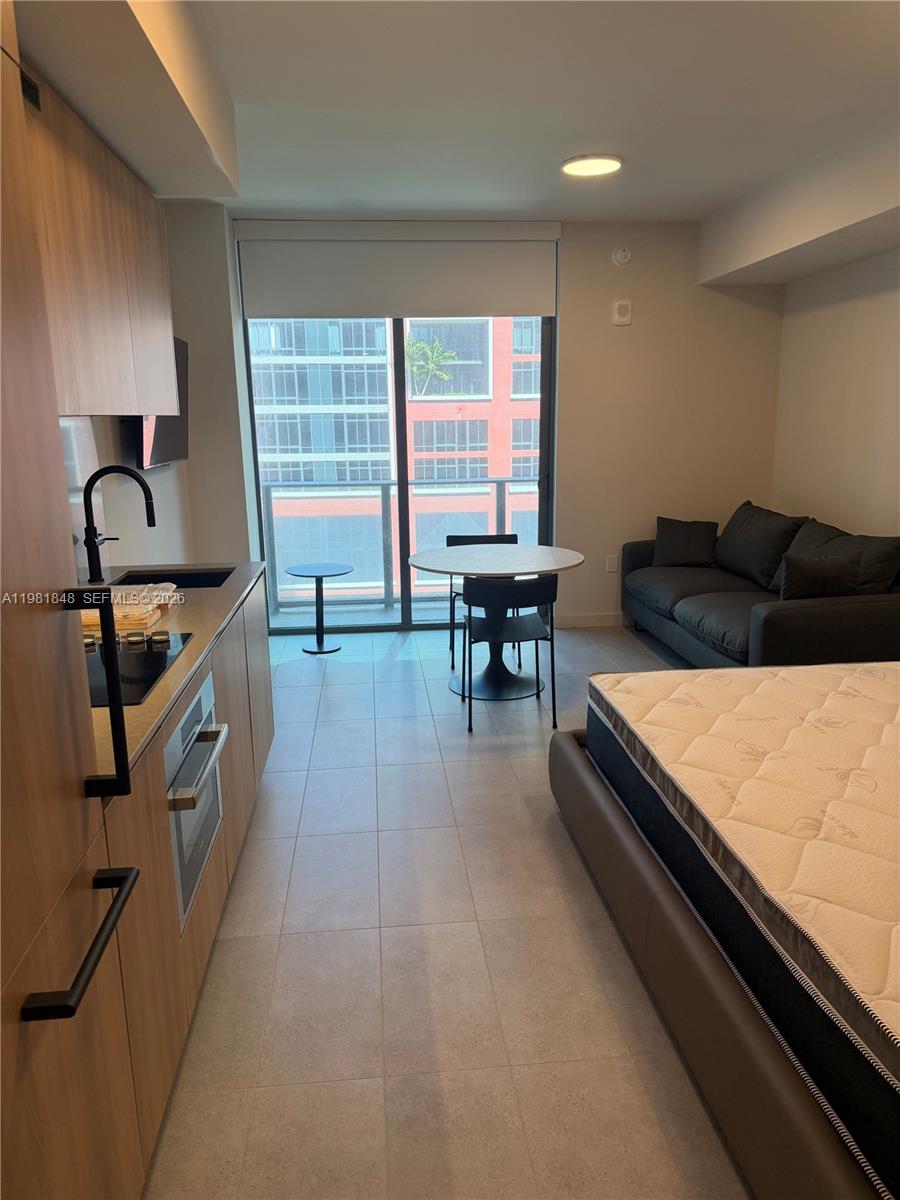 A studio apartment features a kitchenette, dining area, and bed with light tile flooring — 121 NE 5Th ST # 912A, Miami FL 33132, MIAMI, FL