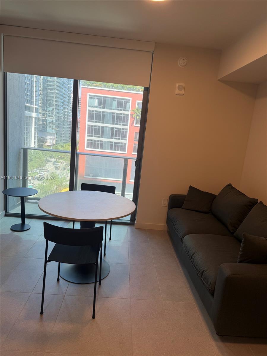A dining area with a round table and sofa sits beside a balcony with city views — 121 NE 5Th ST # 912A, Miami FL 33132, MIAMI, FL