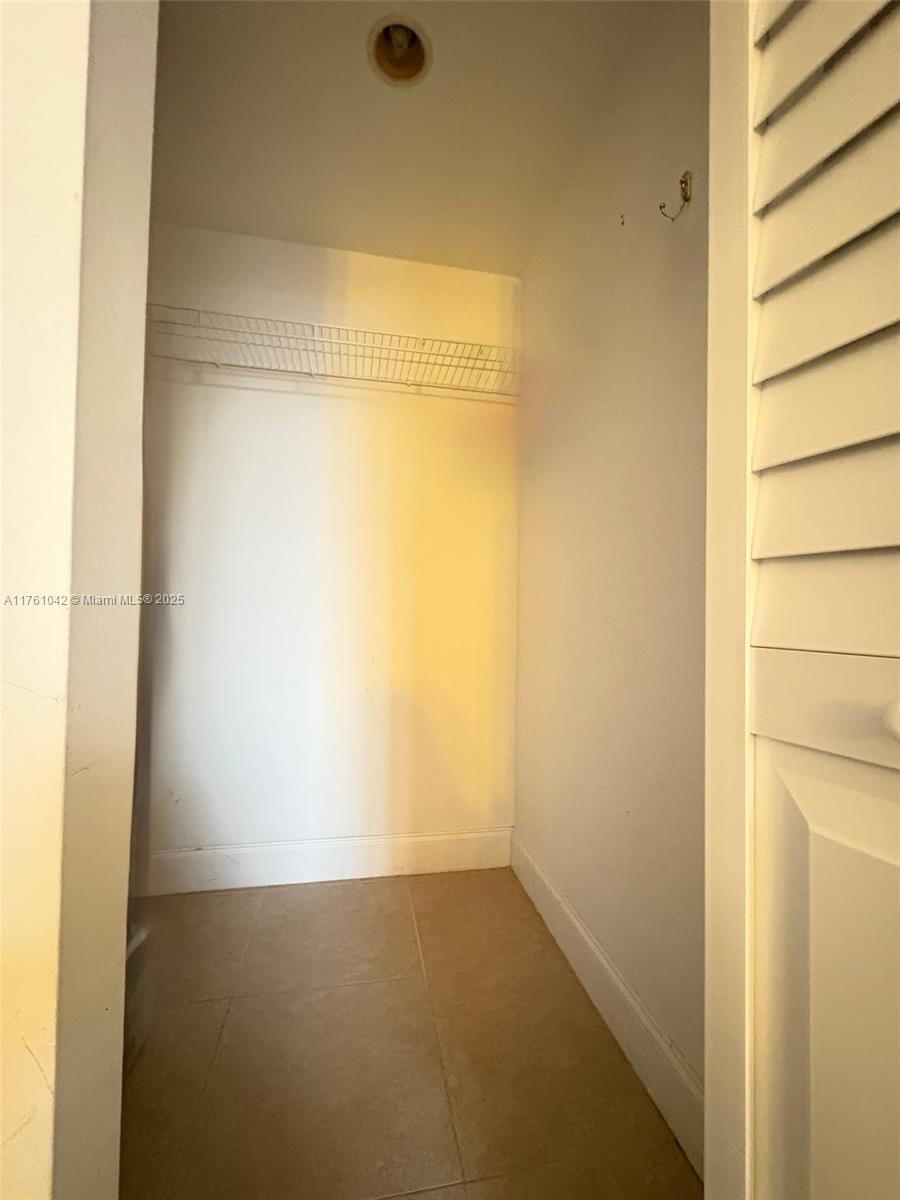 A small walk-in closet features white walls, a wire shelf, and light-colored tile flooring — 1965 S Ocean Dr # 2F, Hallandale Beach FL 33009, HALLANDALE BEACH, FL