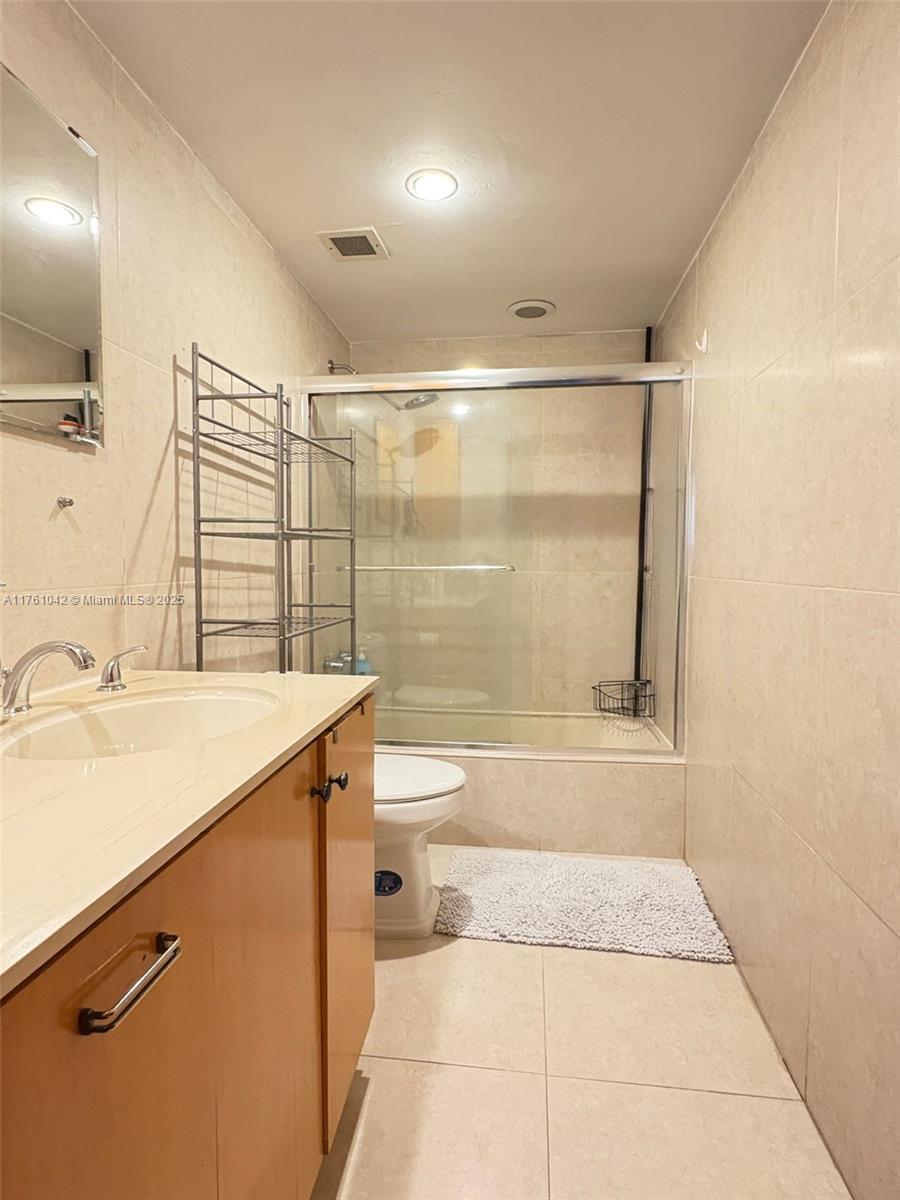 A bathroom features a vanity, a toilet, and a glass-enclosed shower with tiled walls — 1965 S Ocean Dr # 2F, Hallandale Beach FL 33009, HALLANDALE BEACH, FL