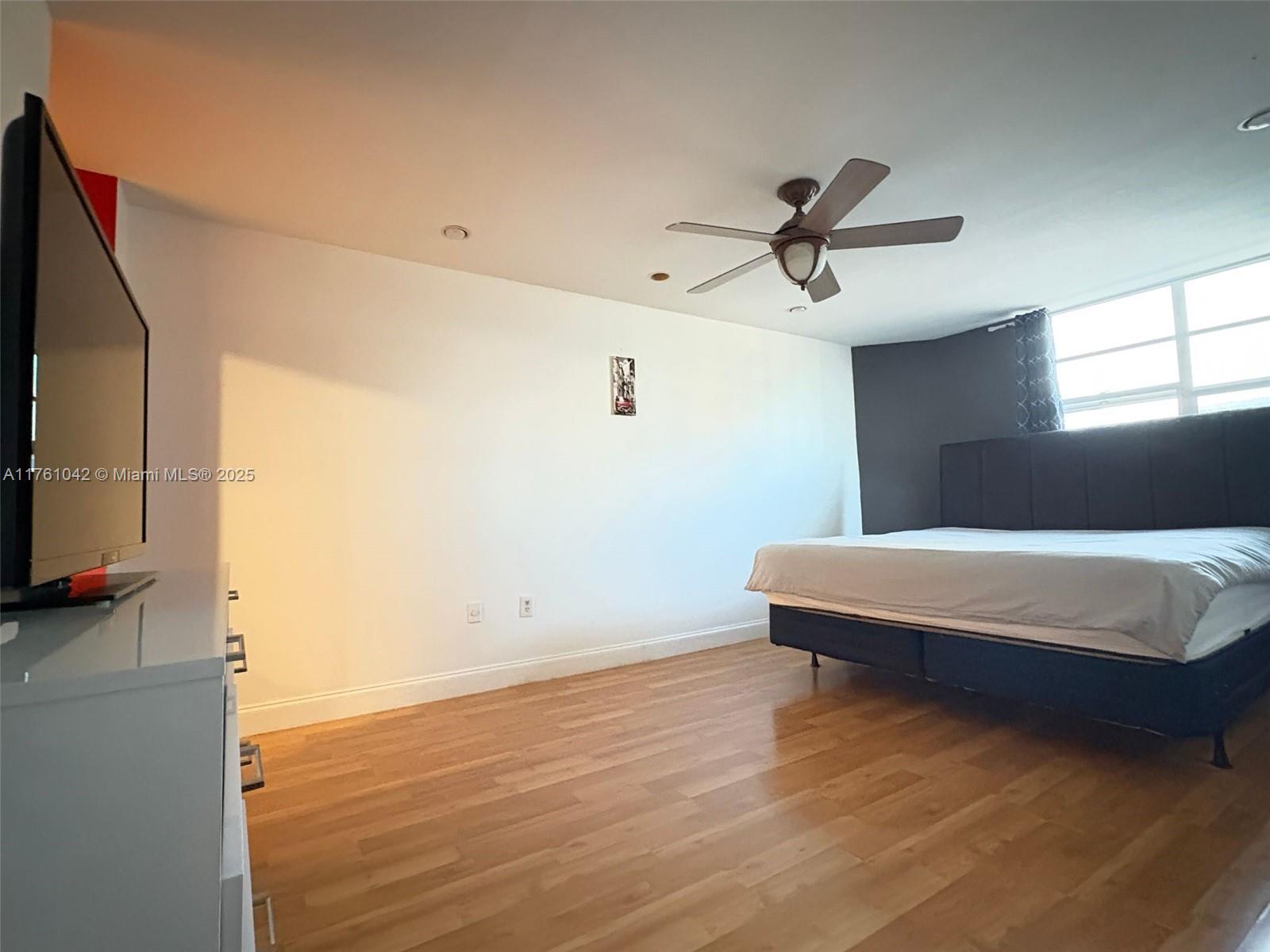 A bedroom features wood flooring, a ceiling fan, a television, and a bed — 1965 S Ocean Dr # 2F, Hallandale Beach FL 33009, HALLANDALE BEACH, FL