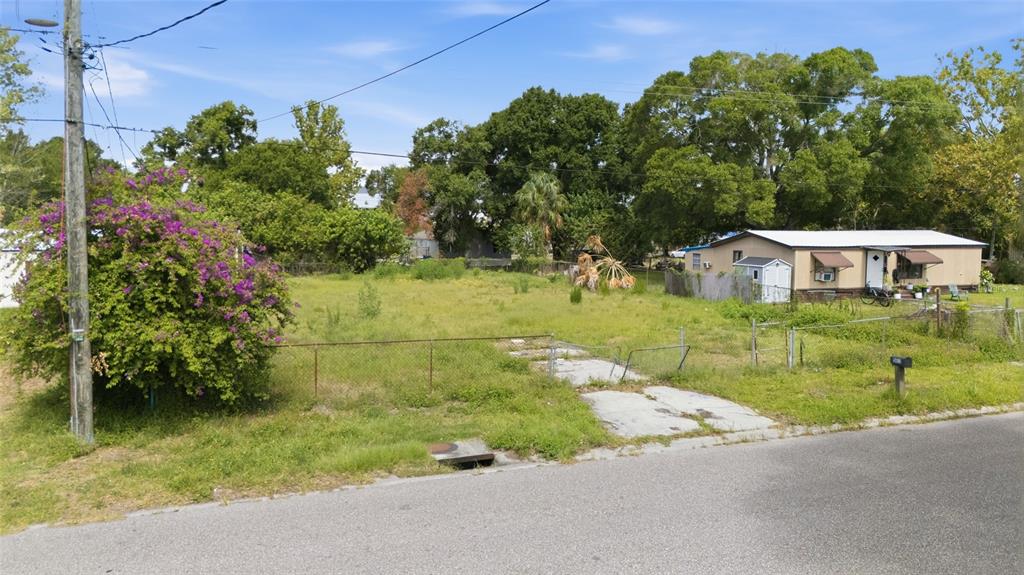 A vacant grassy lot sits next to a single-story house with a small shed — 5013 DACCA DRIVE, TAMPA, FL