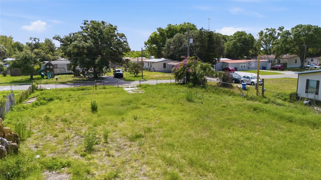 An elevated view of a vacant, grassy residential lot with surrounding houses and trees — 5013 DACCA DRIVE, TAMPA, FL