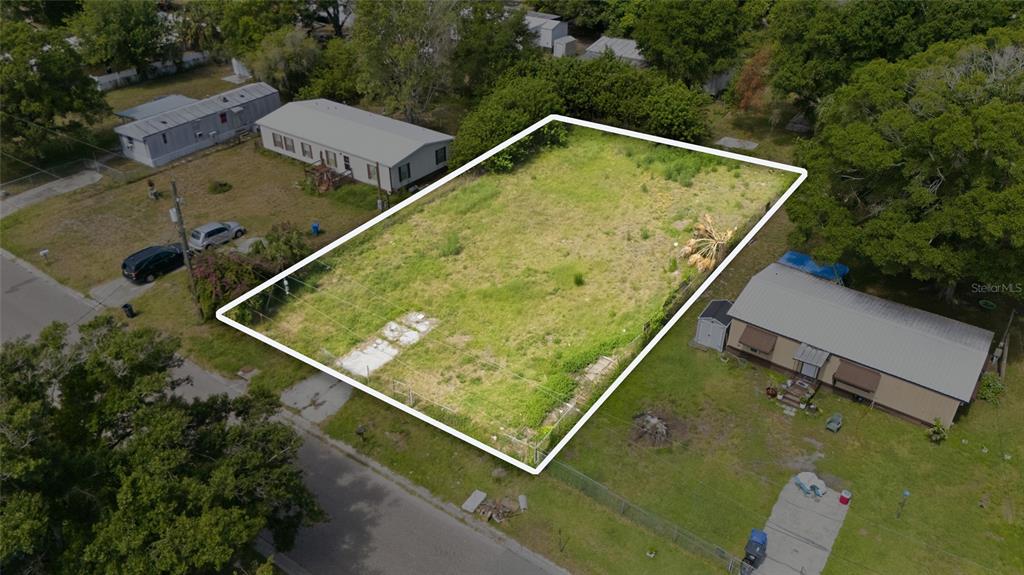 An aerial view shows a vacant, rectangular residential lot outlined in white between two houses — 5013 DACCA DRIVE, TAMPA, FL
