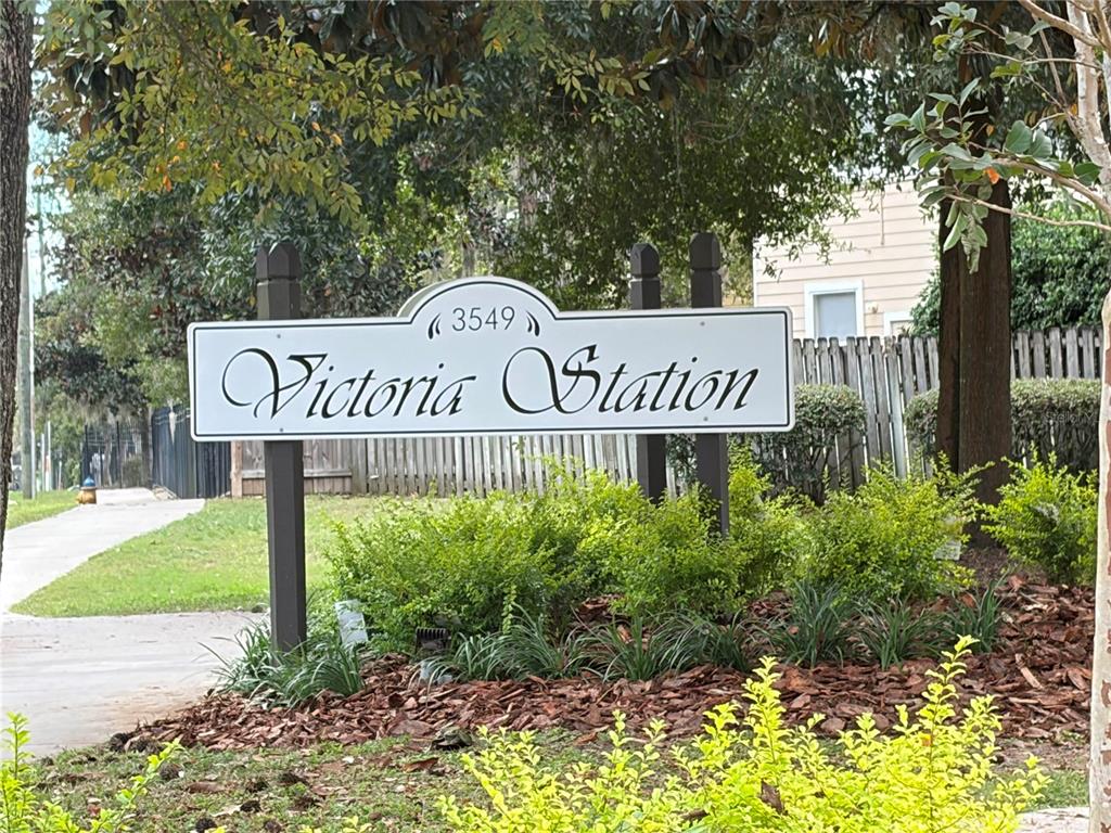 A white sign with the text Victoria Station stands in a landscaped residential area — 3521 SW 30TH WAY UNIT 105, GAINESVILLE, FL