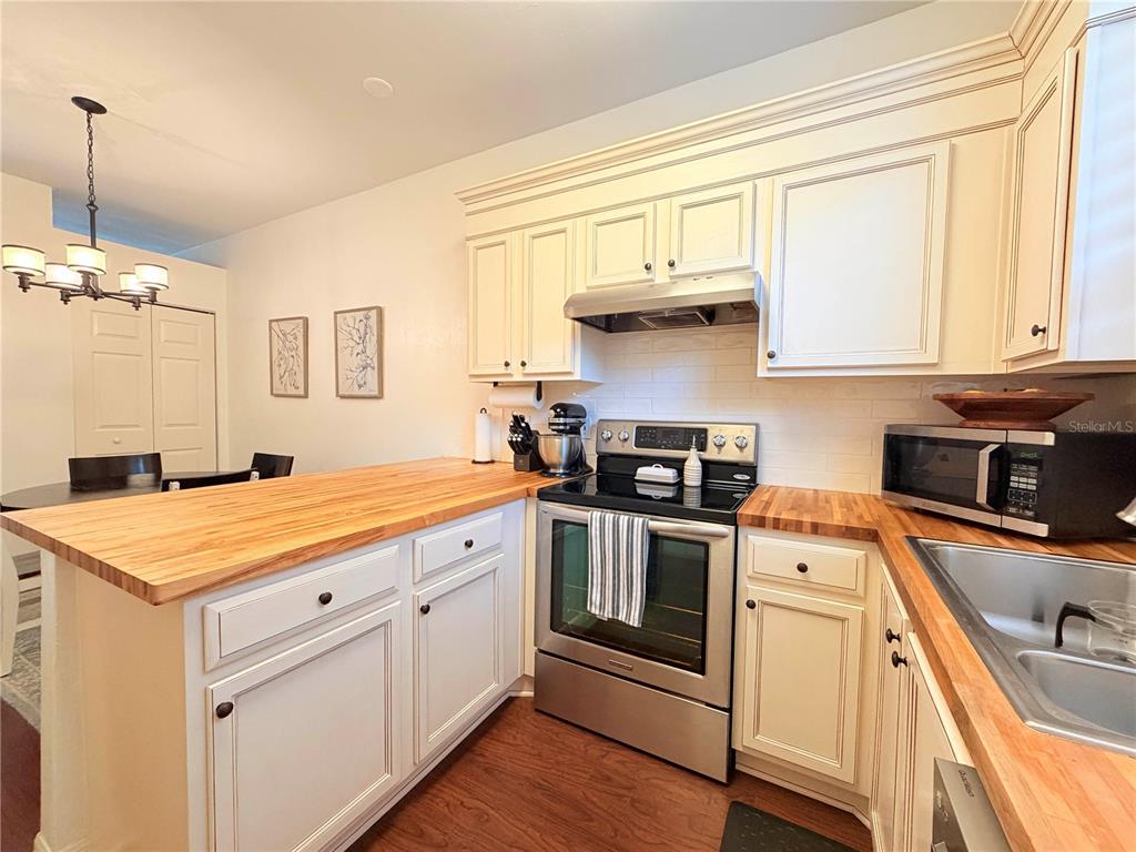 A kitchen featuring white cabinets, a butcher block countertop, and stainless steel appliances — 3521 SW 30TH WAY UNIT 105, GAINESVILLE, FL