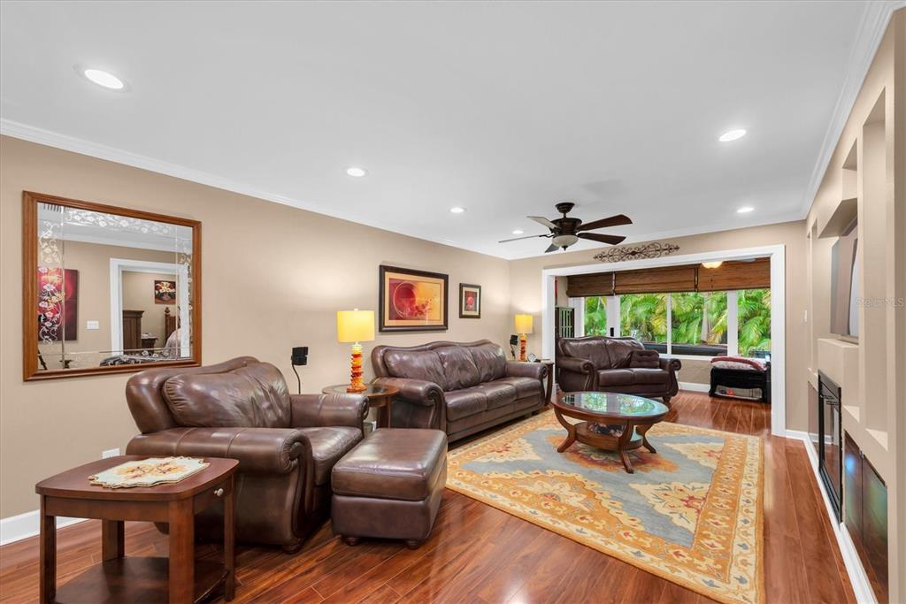 A living room features leather furniture, a patterned area rug, and hardwood floors — 19029 US HIGHWAY 19 N UNIT 13E, CLEARWATER, FL