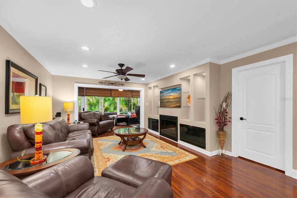 A living room features leather furniture, a fireplace with built-in shelving, and hardwood flooring — 19029 US HIGHWAY 19 N UNIT 13E, CLEARWATER, FL