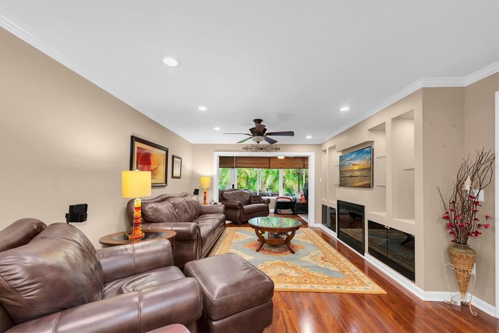 A living room with leather furniture, a fireplace, built-in shelving, and hardwood floors — 19029 US HIGHWAY 19 N UNIT 13E, CLEARWATER, FL