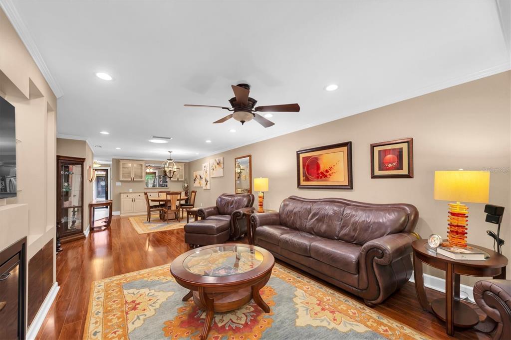 A living room with hardwood floors, a brown leather sofa, and an adjacent dining area — 19029 US HIGHWAY 19 N UNIT 13E, CLEARWATER, FL
