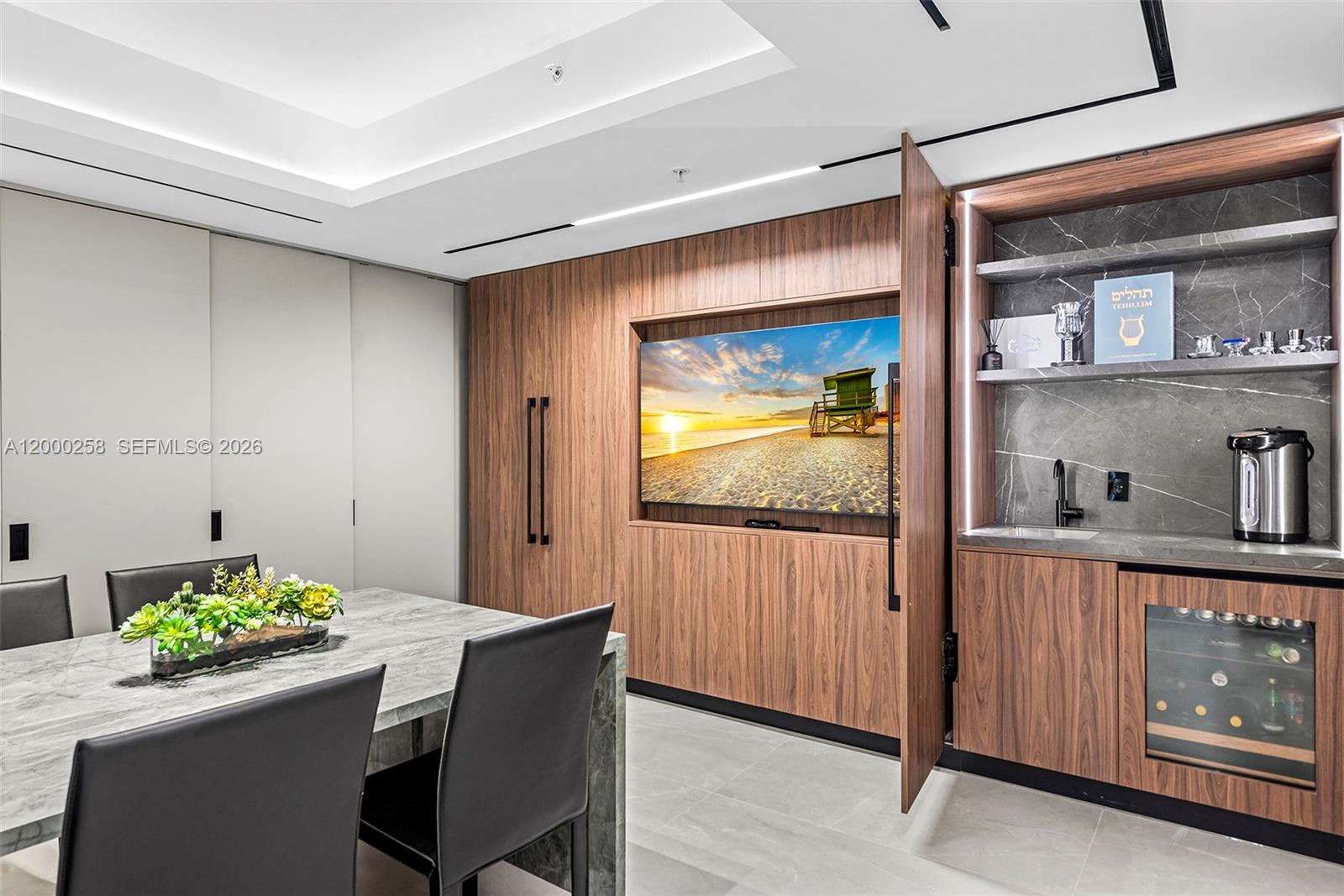 A dining room features a marble table, wood-paneled walls, a built-in television, and a wet bar — SUNNY ISLES BEACH, FL