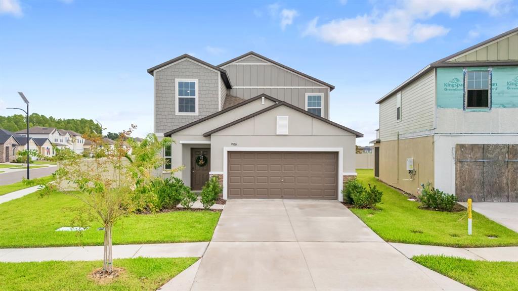 A two-story suburban house with a brown garage door, gray siding, and a front lawn — 9520 RUNAWAY BREEZE, LAND O LAKES, FL
