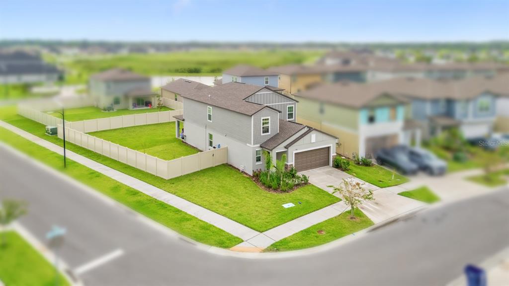 An aerial view shows a two-story suburban house with a fenced yard on a corner lot — 9520 RUNAWAY BREEZE, LAND O LAKES, FL