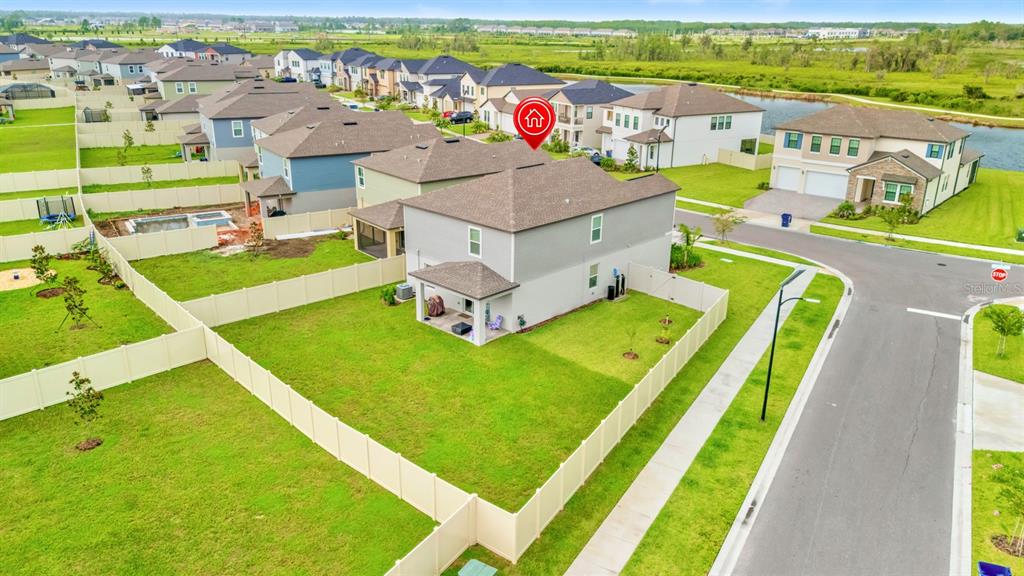 An aerial view shows a two-story suburban house with a fenced backyard and lawn — 9520 RUNAWAY BREEZE, LAND O LAKES, FL