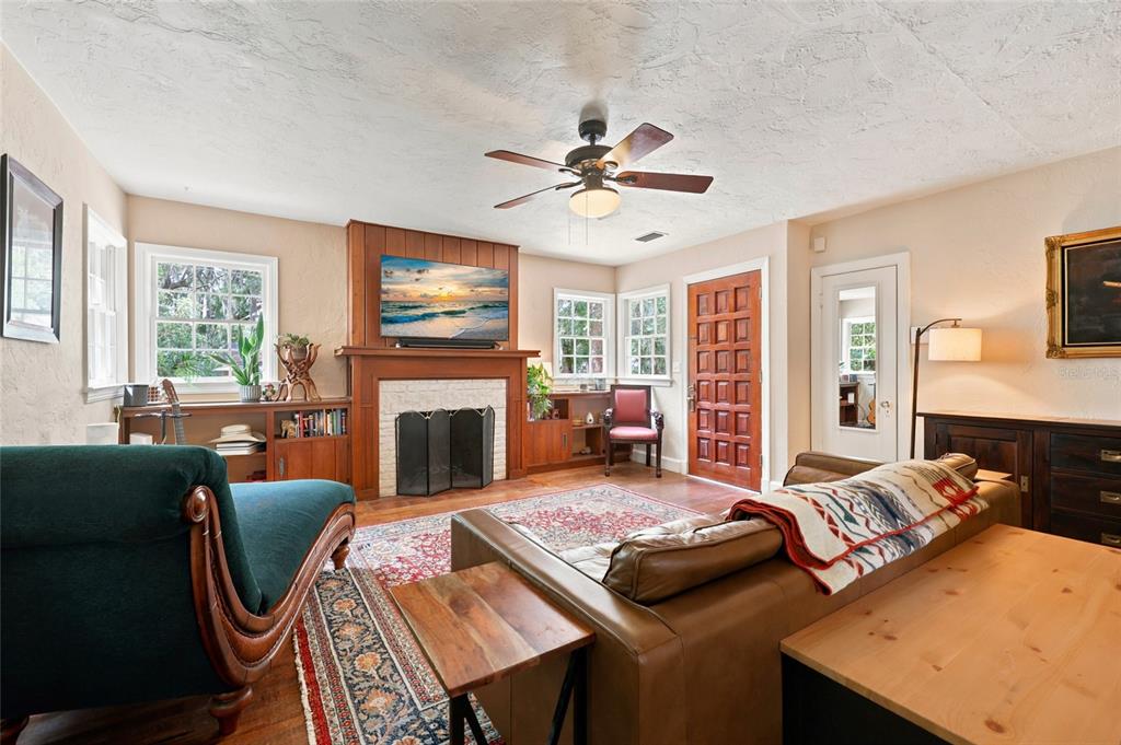 A living room features a fireplace with a mounted television, wood flooring, and a ceiling fan — 616 NW 8TH PLACE, GAINESVILLE, FL