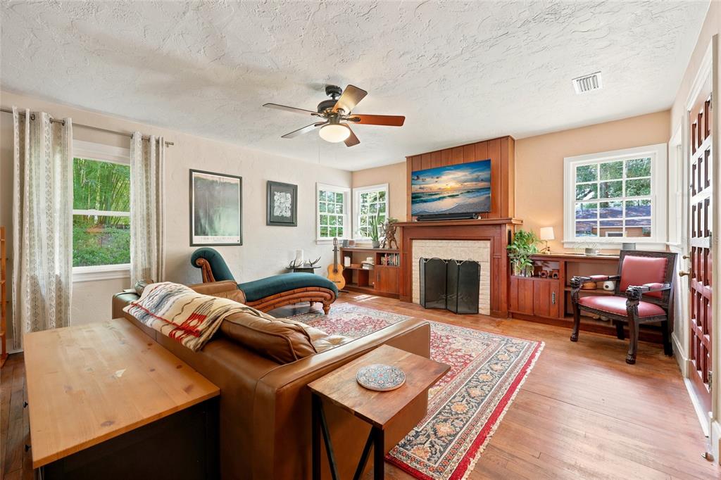 A living room features a fireplace, wood floors, a leather sofa, and a ceiling fan — 616 NW 8TH PLACE, GAINESVILLE, FL
