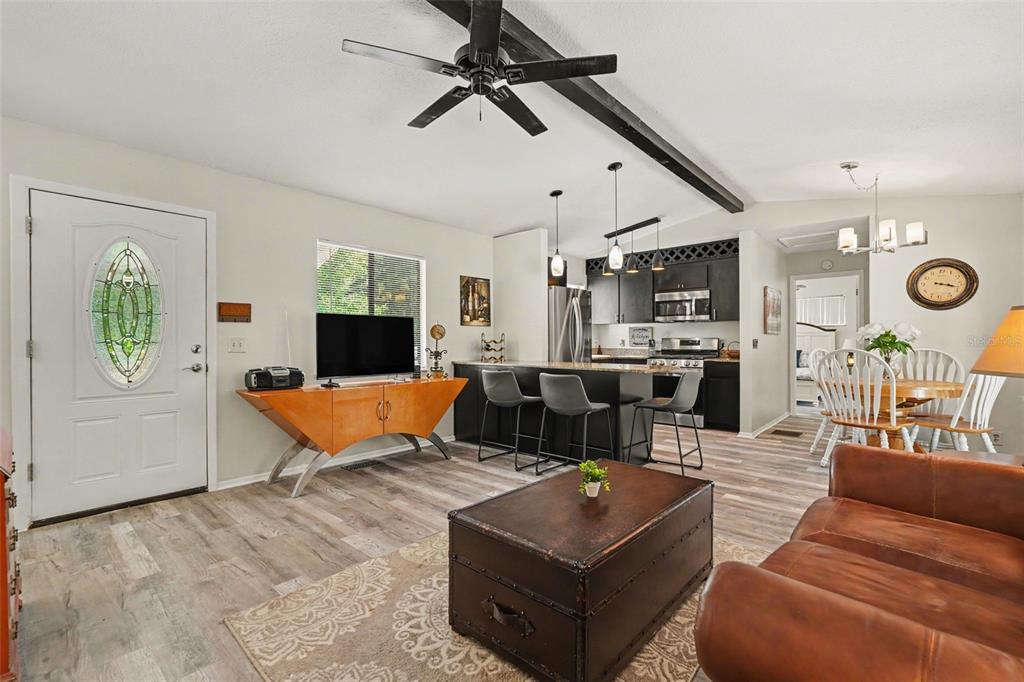 A living room and kitchen area with wood-look flooring, a ceiling fan, and bar seating — 7269 W RAYBURN ST, DUNNELLON, FL
