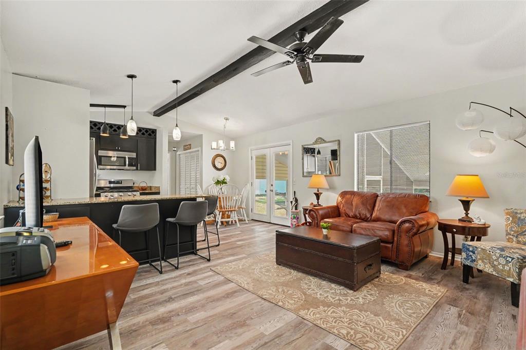 An open-concept living room and kitchen feature wood-look flooring, a leather sofa, and dark cabinetry — 7269 W RAYBURN ST, DUNNELLON, FL