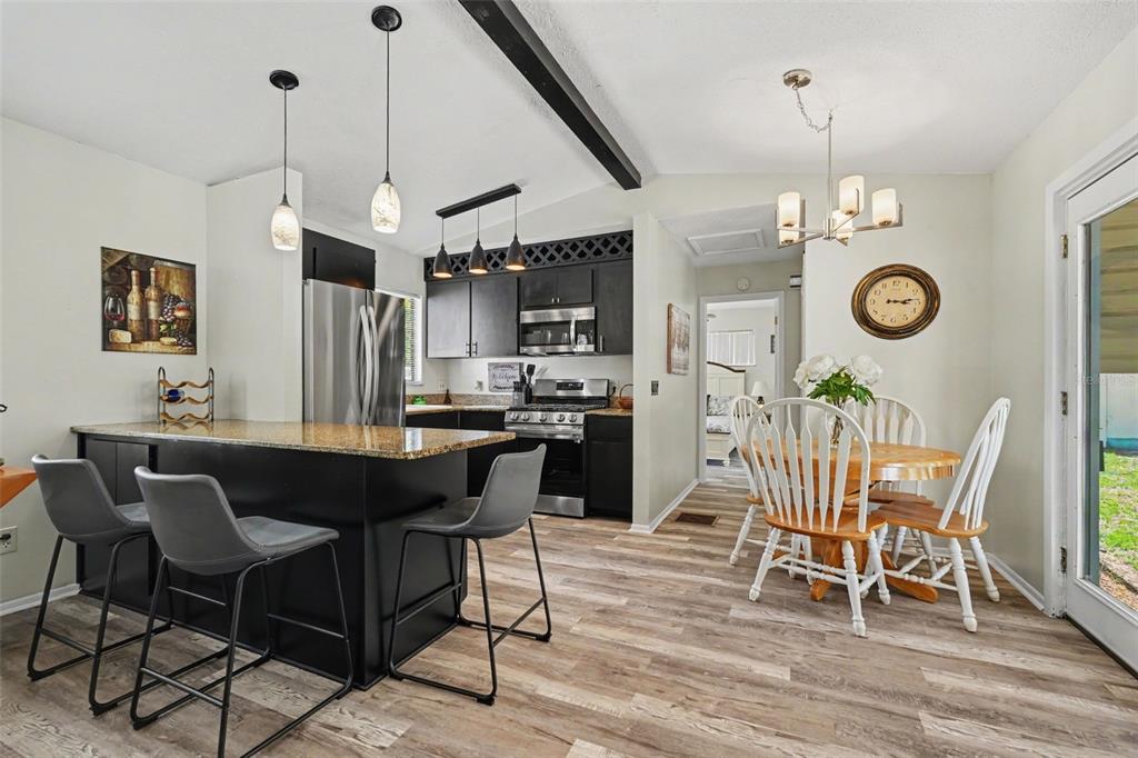 A kitchen and dining area with dark cabinets, a granite island, and wood-look flooring — 7269 W RAYBURN ST, DUNNELLON, FL