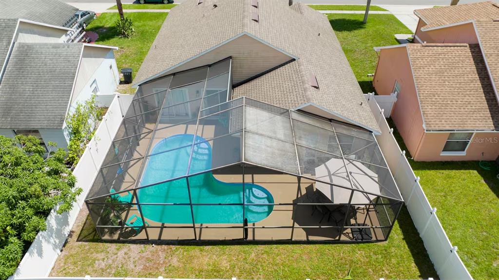 An aerial view shows a house with a screened-in pool enclosure and a backyard — 751 COUNTRY WOODS CIRCLE, KISSIMMEE, FL