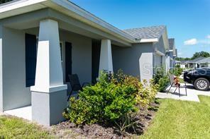 A gray house with a covered front porch, white columns, and a small landscaped garden — 3882 WILLOW RIDGE DRIVE, LAKELAND, FL