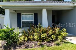 The exterior of a house features a covered porch with two white columns and landscaping — 3882 WILLOW RIDGE DRIVE, LAKELAND, FL