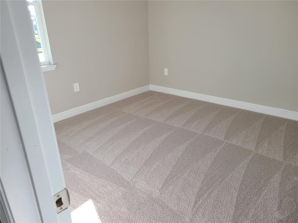 An empty bedroom features beige walls, white trim, and light-colored wall-to-wall carpeting — 17758 CANTARINA COVE, LAKEWOOD RANCH, FL