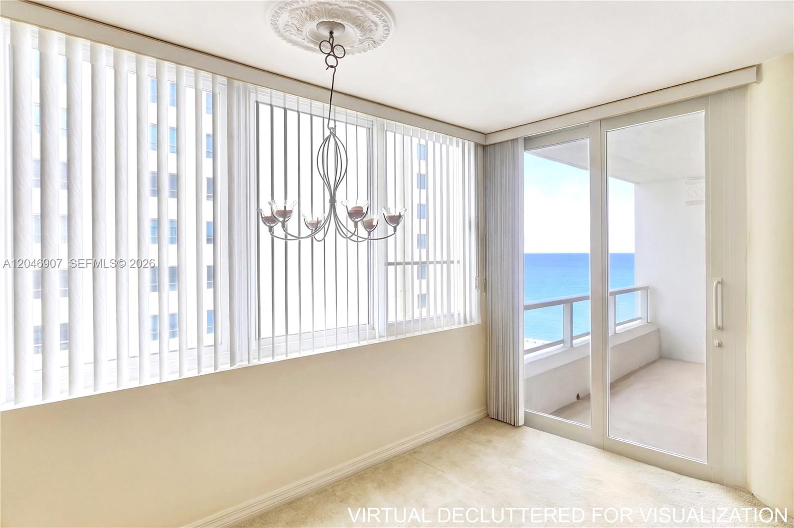 An empty room with a chandelier, vertical blinds, and a sliding door to a balcony — 5005 Collins Ave # 1224, Miami Beach FL 33140, MIAMI BEACH, FL