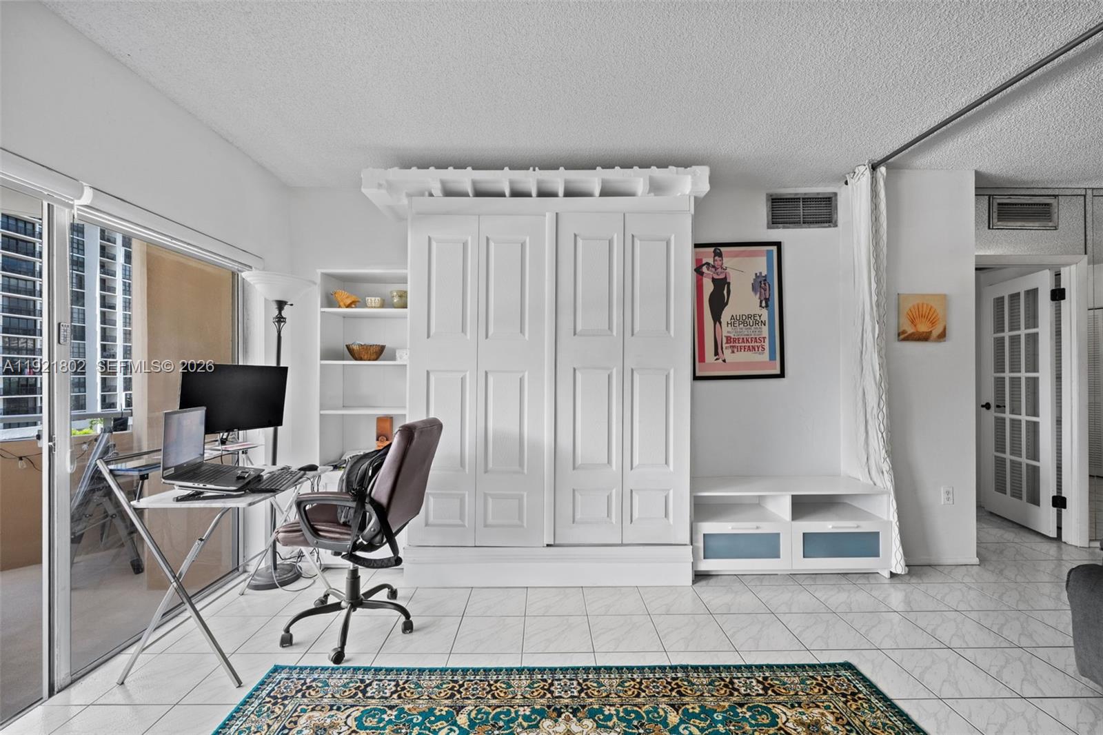 A room features a large white wardrobe, a desk with computer equipment, and tile flooring — 1985 S Ocean Dr # 3A, Hallandale Beach FL 33009, HALLANDALE BEACH, FL