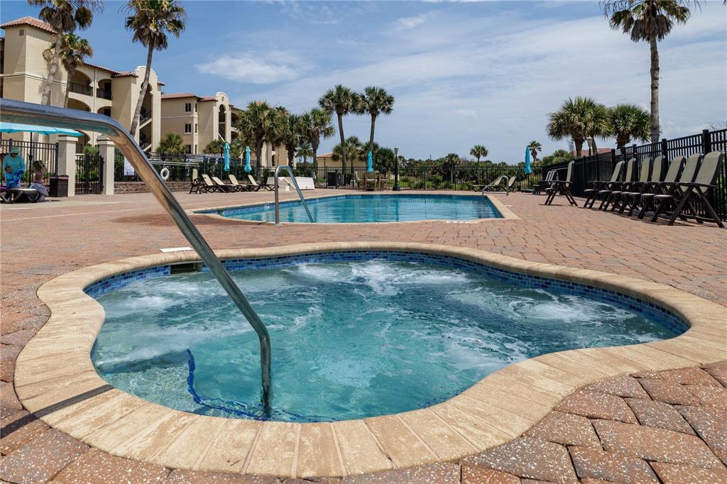 A hot tub in the foreground overlooks a swimming pool on a brick patio — 2450 N OCEAN SHORE BOULEVARD UNIT 313C, FLAGLER BEACH, FL