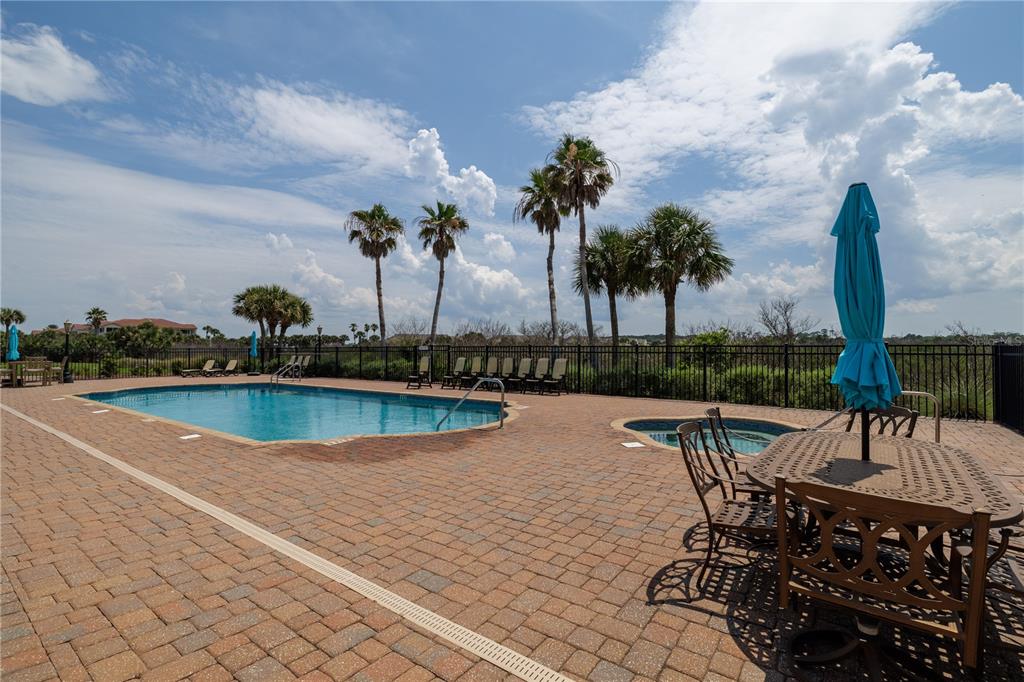 A swimming pool and hot tub are surrounded by a brick patio and palm trees — 2450 N OCEAN SHORE BOULEVARD UNIT 313C, FLAGLER BEACH, FL