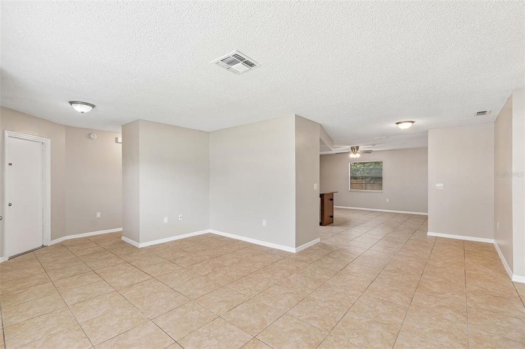 An open-concept living area features beige tile flooring, light-colored walls, and a ceiling fan — 8526 HUNTSMAN LANE, PORT RICHEY, FL