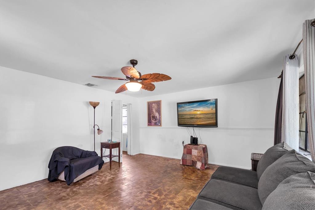 A living room features tile flooring, a ceiling fan, a wall-mounted television, and furniture — 1846 51ST STREET S, GULFPORT, FL