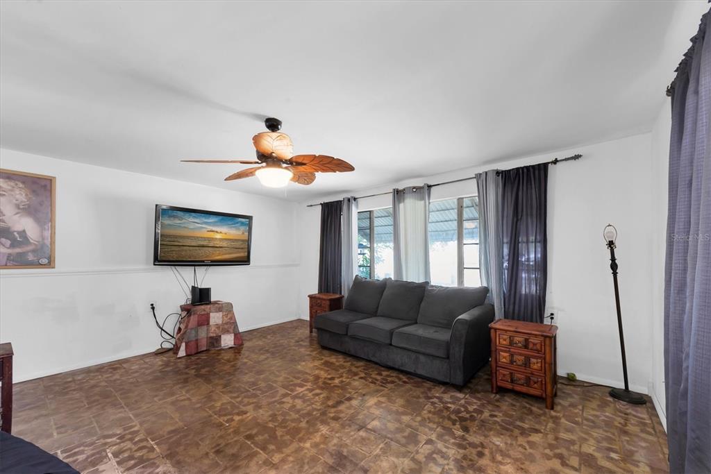 A living room features a dark gray sofa, a ceiling fan, and tiled flooring — 1846 51ST STREET S, GULFPORT, FL