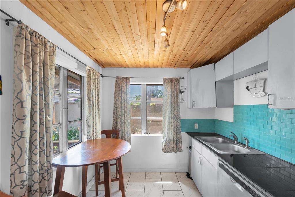 A kitchen features a wood-paneled ceiling, teal subway tile backsplash, and a small dining table — 1846 51ST STREET S, GULFPORT, FL
