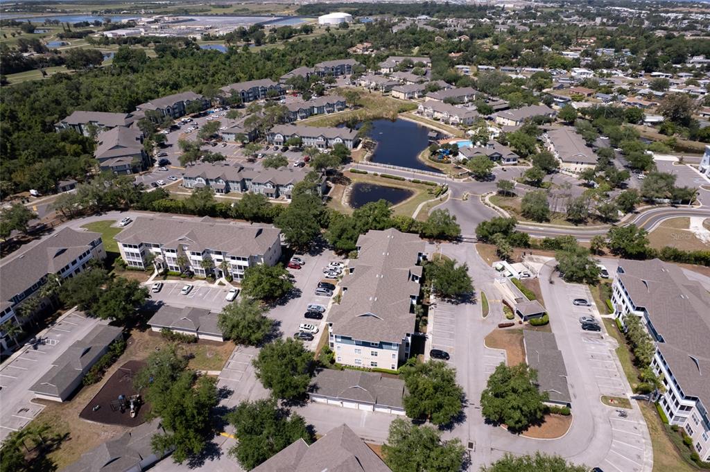 An aerial view shows a multi-building apartment complex with parking lots and a central pond — 4802 51ST STREET W UNIT 1015, BRADENTON, FL