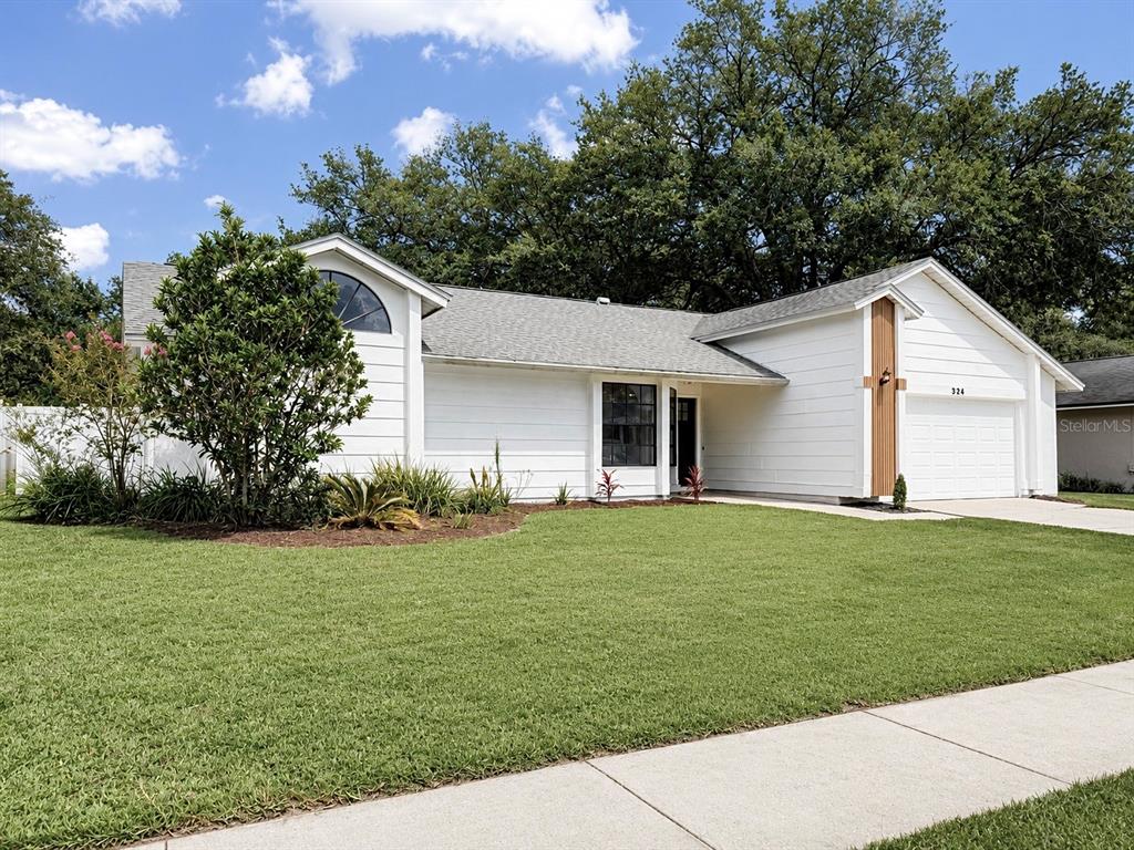 A white, single-story house with a front-facing garage and a large, manicured lawn — 324 RINGWOOD CIRCLE, WINTER SPRINGS, FL