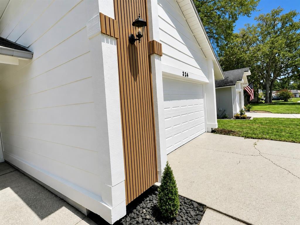 A white house exterior features a vertical wood-slat accent wall and a garage — 324 RINGWOOD CIRCLE, WINTER SPRINGS, FL