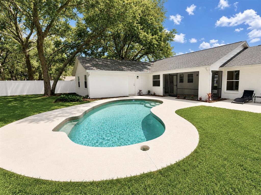 A backyard features a kidney-shaped swimming pool surrounded by a concrete deck and lawn — 324 RINGWOOD CIRCLE, WINTER SPRINGS, FL