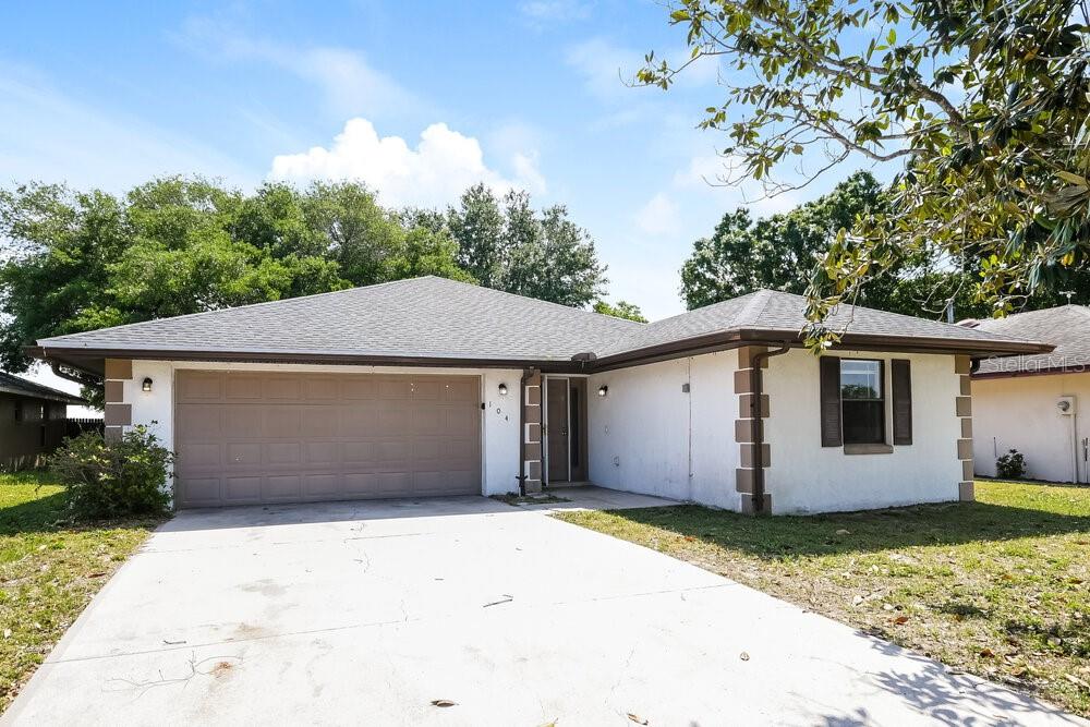 A single-story house with a white exterior, a two-car garage, and a concrete driveway — 104 LAKE DAISY TERRACE, WINTER HAVEN, FL